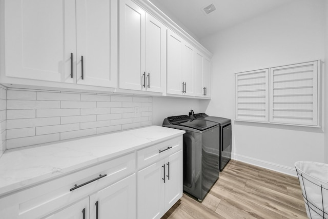 washroom with cabinets, light hardwood / wood-style flooring, and washer and clothes dryer