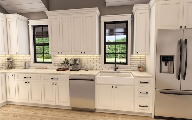 kitchen featuring appliances with stainless steel finishes, light stone counters, light wood-type flooring, and a healthy amount of sunlight