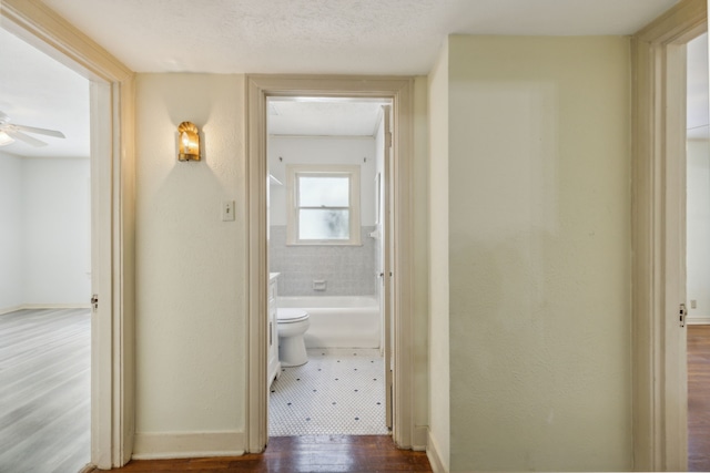 corridor featuring a textured ceiling and hardwood / wood-style flooring