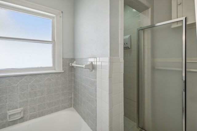 bathroom featuring tile walls and separate shower and tub