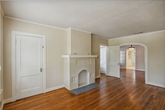 unfurnished living room featuring ornamental molding, dark wood-type flooring, and a brick fireplace