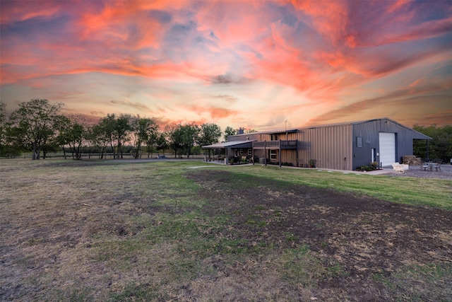 yard at dusk featuring a garage and an outbuilding