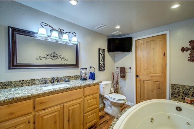 bathroom featuring toilet, a tub to relax in, vanity, and hardwood / wood-style floors