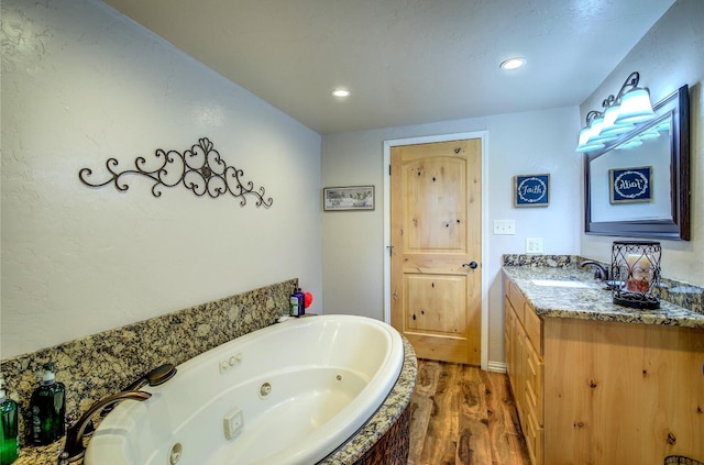 bathroom featuring vanity, hardwood / wood-style flooring, and a bath