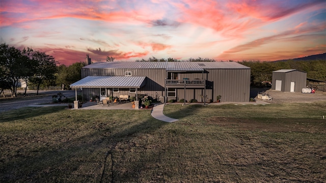 back house at dusk with a storage unit, a yard, and a patio area