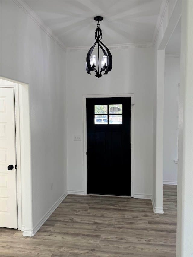 foyer with an inviting chandelier, ornamental molding, and light wood-type flooring