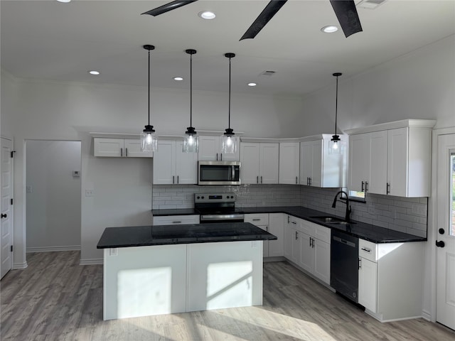 kitchen with pendant lighting, a kitchen island, white cabinetry, and stainless steel appliances