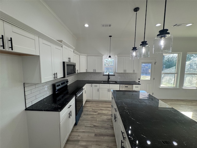 kitchen featuring black / electric stove, light hardwood / wood-style floors, white cabinetry, and decorative light fixtures