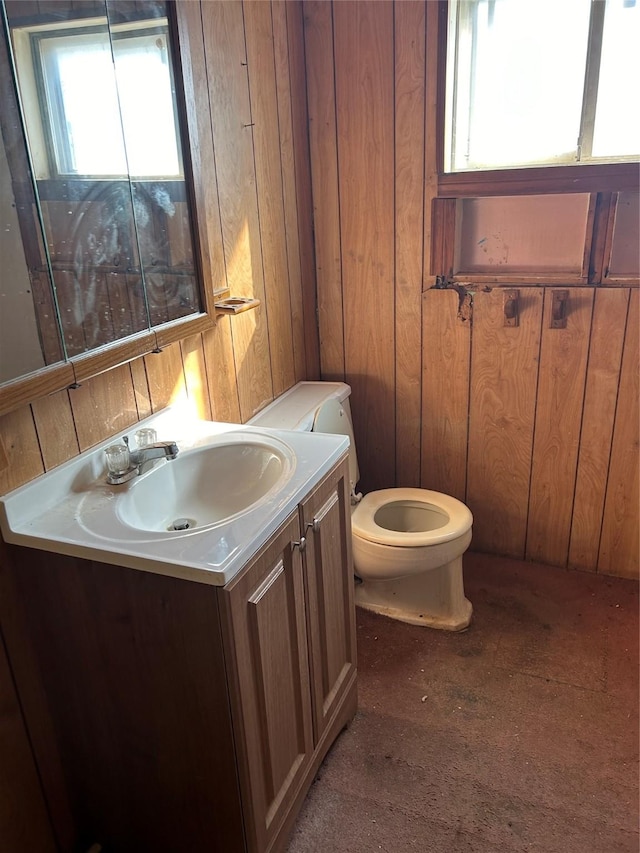 bathroom featuring toilet, vanity, and wooden walls