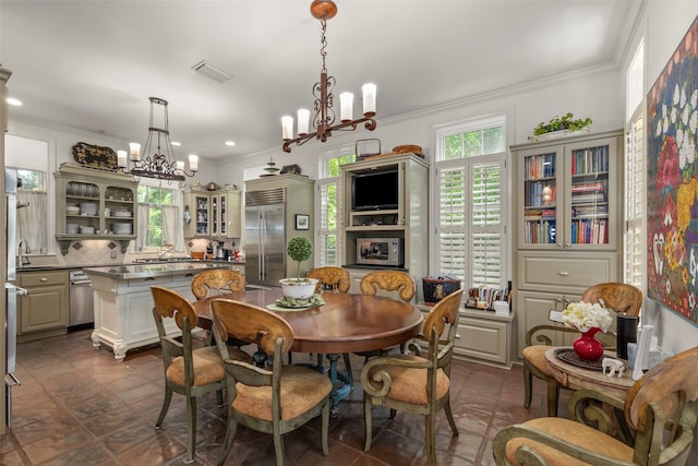 dining area with sink, a chandelier, and crown molding