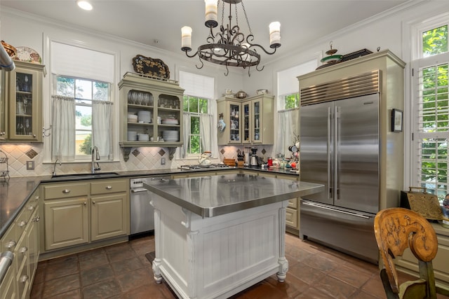 kitchen featuring decorative backsplash, sink, a center island, a chandelier, and appliances with stainless steel finishes