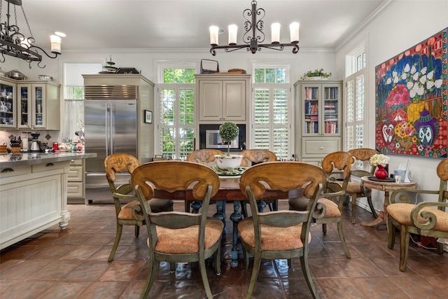 dining space featuring an inviting chandelier, dark tile patterned floors, and crown molding