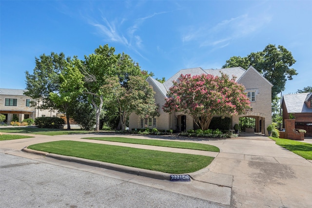 view of property hidden behind natural elements featuring a front lawn and a carport