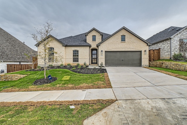 french country style house with a garage and a front lawn