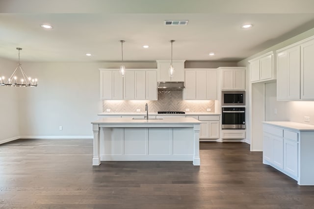 kitchen featuring built in microwave, white cabinetry, oven, and pendant lighting