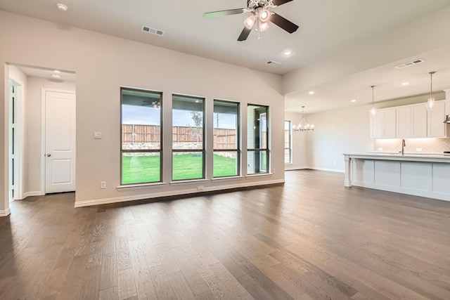 unfurnished living room featuring dark hardwood / wood-style floors and ceiling fan with notable chandelier