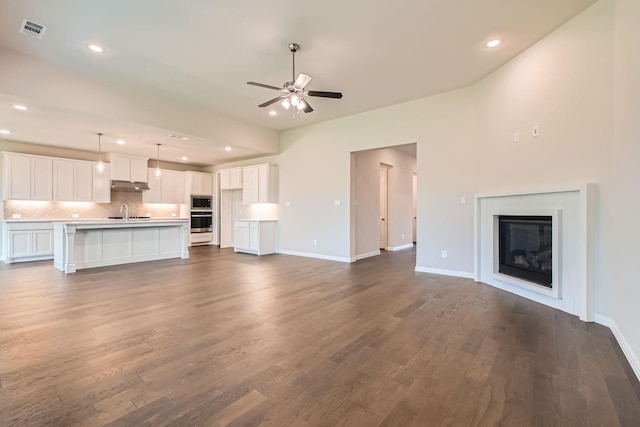 unfurnished living room with sink, dark wood-type flooring, and ceiling fan