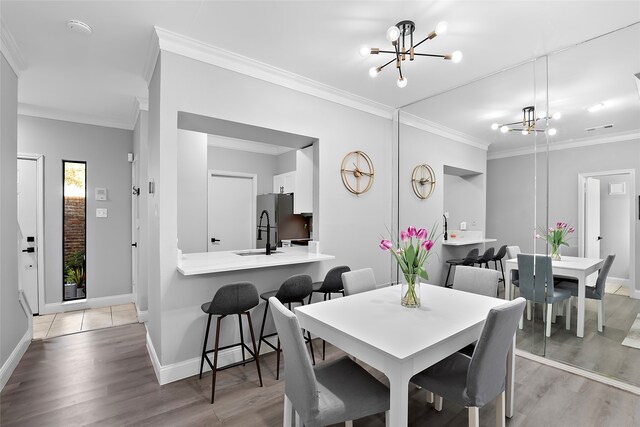 dining space featuring an inviting chandelier, light hardwood / wood-style flooring, ornamental molding, and sink