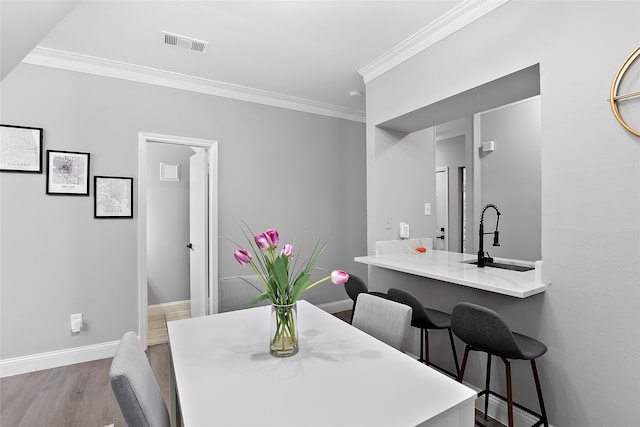 dining space with crown molding, wood-type flooring, and sink