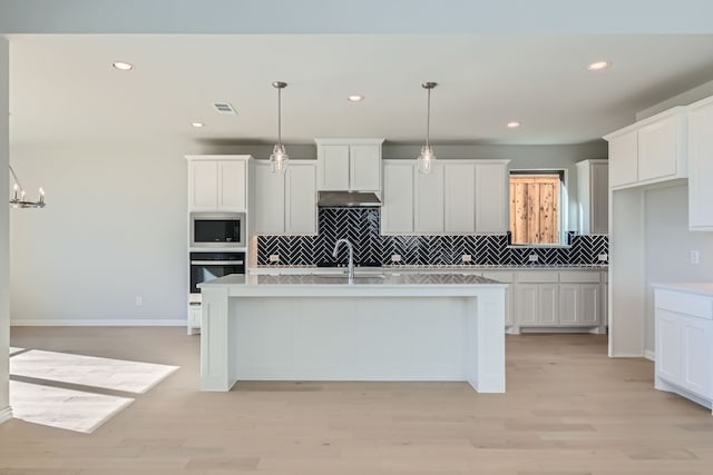 kitchen with light hardwood / wood-style floors, white cabinetry, hanging light fixtures, and sink