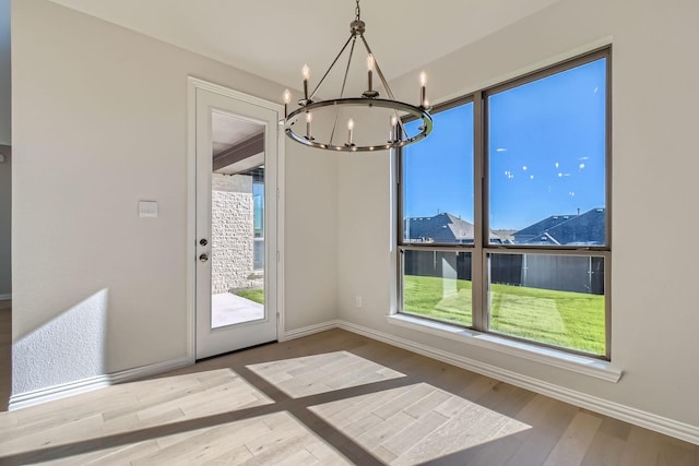 unfurnished dining area with a notable chandelier and wood-type flooring