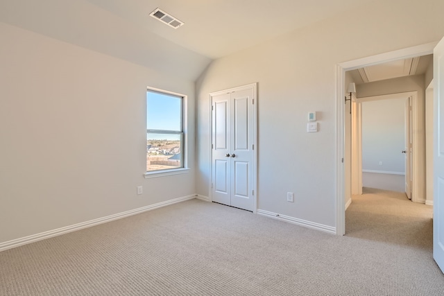 unfurnished bedroom featuring light carpet, a closet, and lofted ceiling