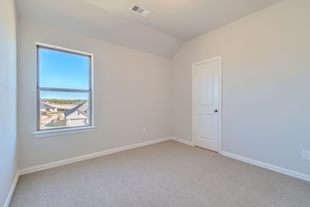 carpeted empty room featuring vaulted ceiling and plenty of natural light