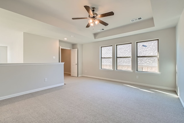 carpeted empty room featuring a raised ceiling and ceiling fan