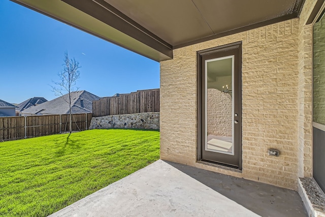 view of exterior entry featuring a yard and a patio area