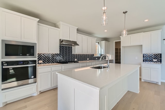 kitchen featuring sink, light wood-type flooring, a center island with sink, and appliances with stainless steel finishes