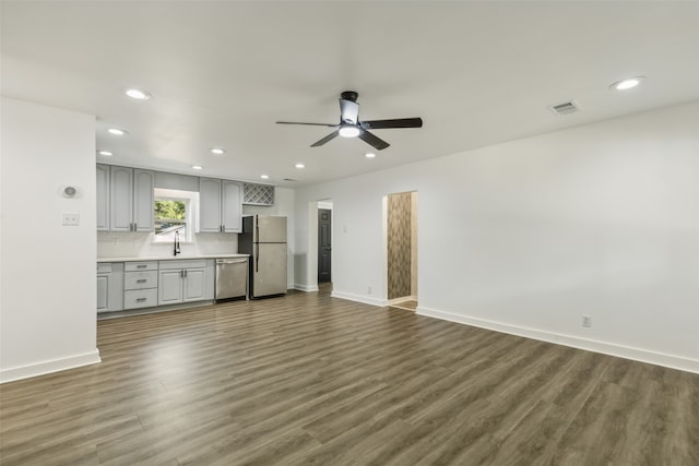 unfurnished living room featuring dark wood-type flooring, ceiling fan, and sink