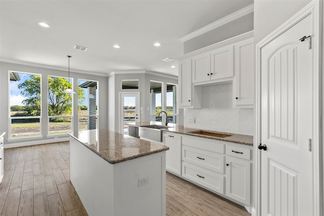 kitchen featuring white cabinetry, dark stone countertops, a wealth of natural light, and light wood-type flooring