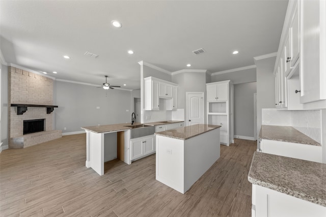 kitchen featuring light hardwood / wood-style flooring, white cabinetry, a fireplace, and a kitchen island