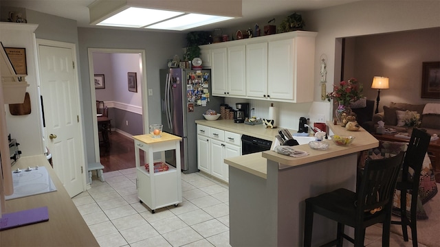 kitchen with stainless steel refrigerator, kitchen peninsula, white cabinets, and a breakfast bar area