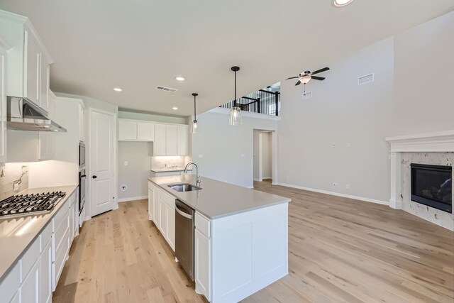 kitchen featuring a kitchen island with sink, sink, white cabinetry, and ventilation hood