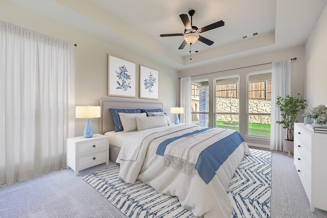 carpeted bedroom featuring a raised ceiling and ceiling fan