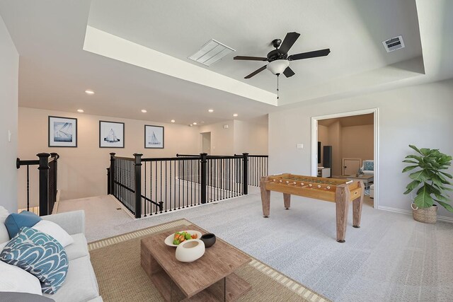 recreation room with light carpet, ceiling fan, and a tray ceiling