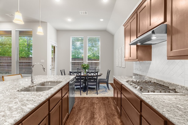 kitchen featuring backsplash, light stone counters, stainless steel appliances, sink, and hanging light fixtures