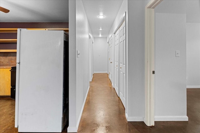 corridor with finished concrete floors and baseboards