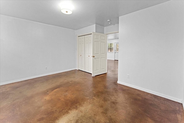 unfurnished room featuring concrete floors and baseboards