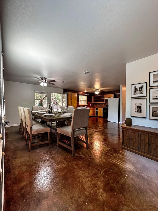 dining area featuring a ceiling fan, concrete floors, and baseboards