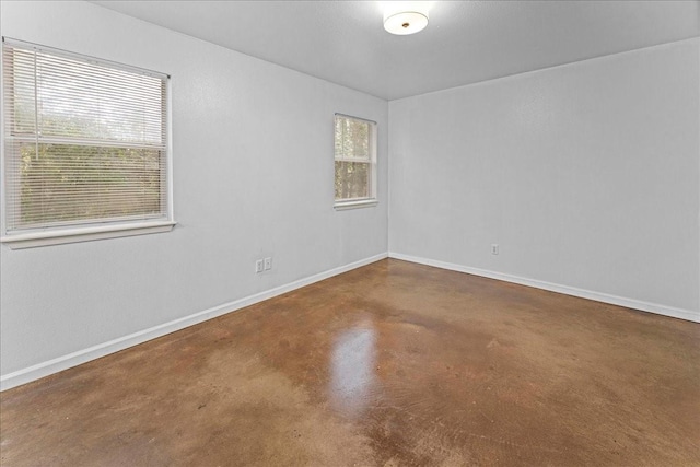 unfurnished room featuring finished concrete floors and baseboards