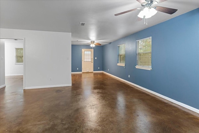 empty room featuring finished concrete floors, visible vents, ceiling fan, and baseboards