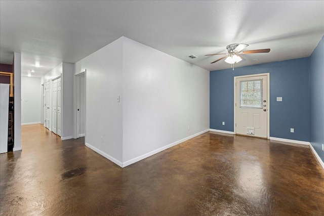 unfurnished room featuring visible vents, concrete floors, a ceiling fan, and baseboards