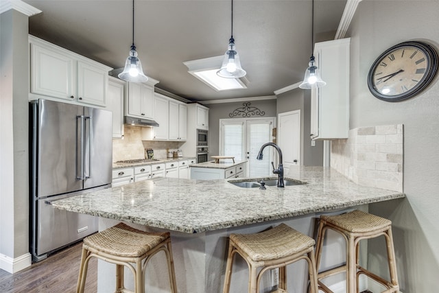 kitchen featuring kitchen peninsula, backsplash, sink, crown molding, and appliances with stainless steel finishes