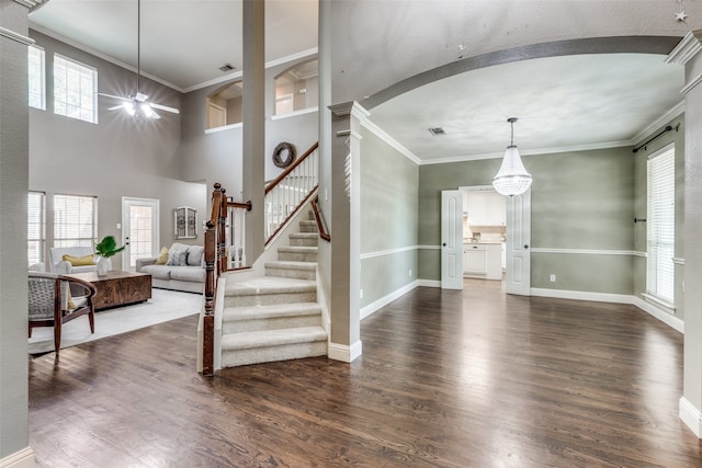 foyer entrance featuring dark wood-type flooring, a notable chandelier, decorative columns, and a healthy amount of sunlight