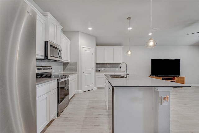 kitchen featuring white cabinetry, stainless steel appliances, sink, and a center island with sink