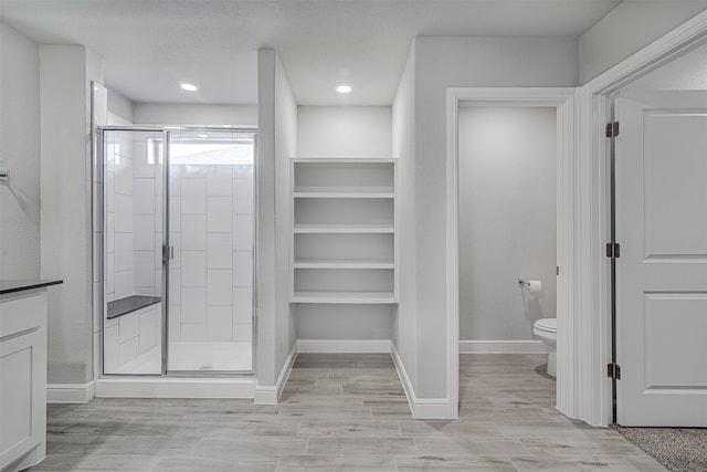 bathroom featuring a shower with door, vanity, wood-type flooring, and toilet