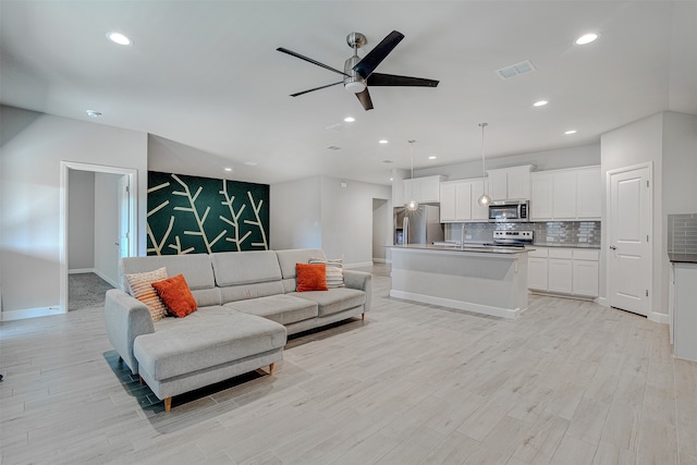 living room with light hardwood / wood-style floors, sink, and ceiling fan