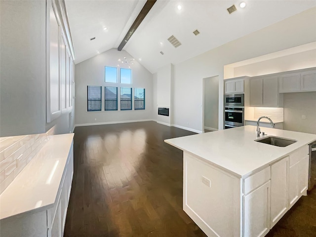kitchen featuring a sink, appliances with stainless steel finishes, light countertops, dark wood finished floors, and backsplash